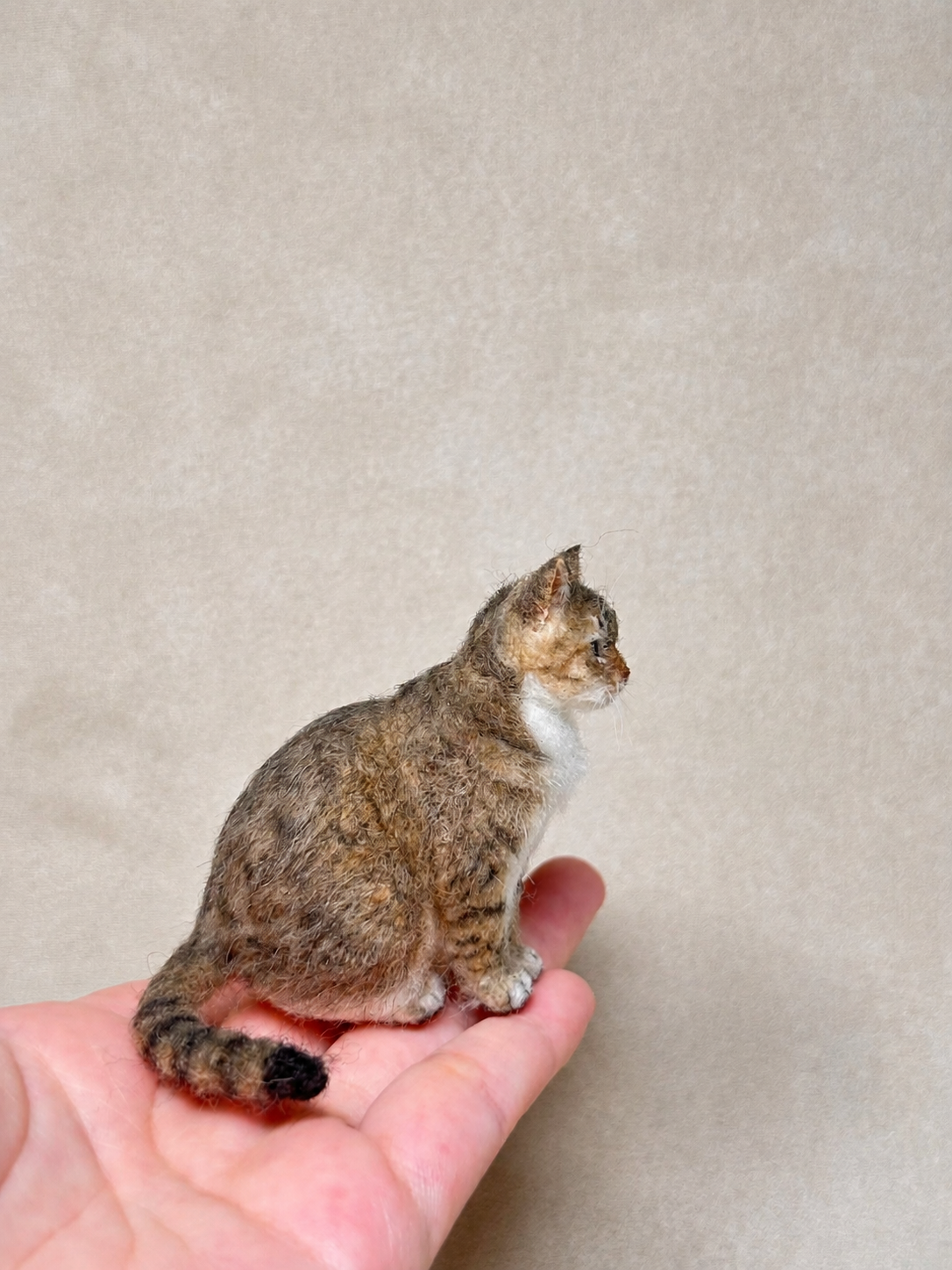 Side view of a handcrafted miniature wool tabby cat figurine