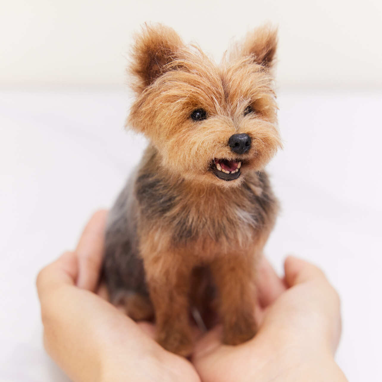 Handcrafted wool pet figurine held gently in two hands