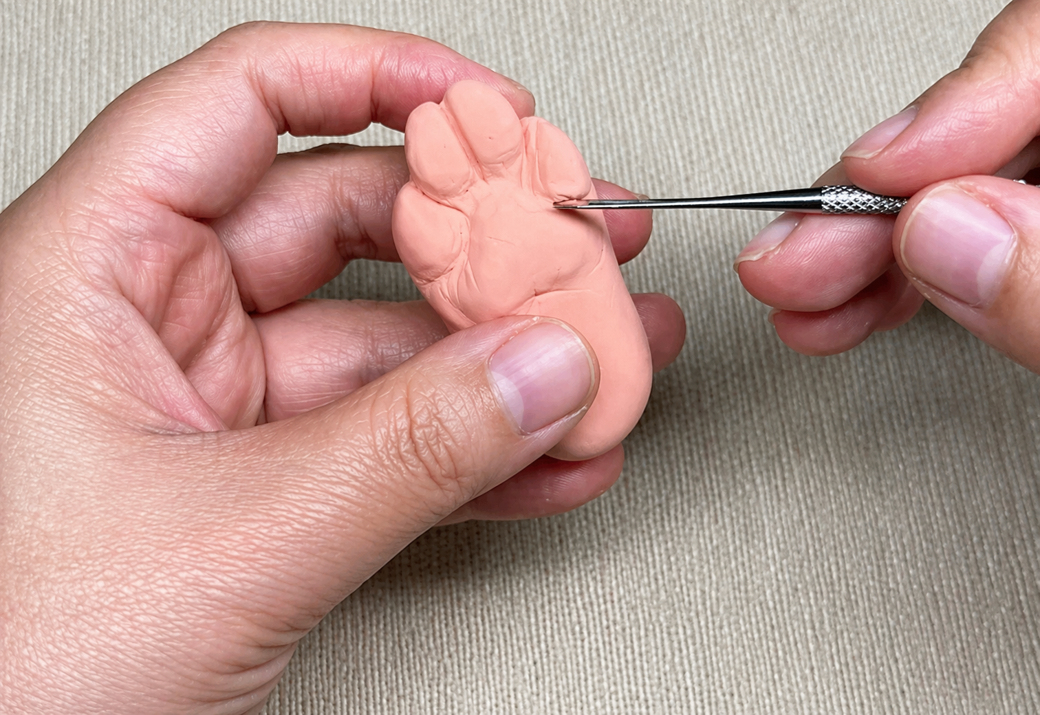 Hand shaping a detailed pet paw for a custom wool portrait